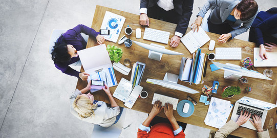 Team Vogelperspektive auf eine Gruppe gemeinsam arbeitender Menschen an einem Schreibtisch