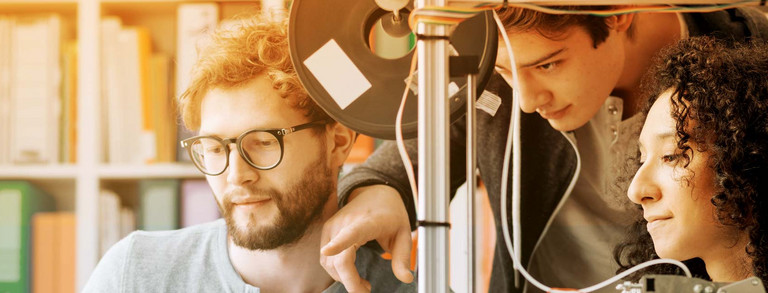 Service Eine Gruppe Studierender arbeitet gemeinsam an Maschine