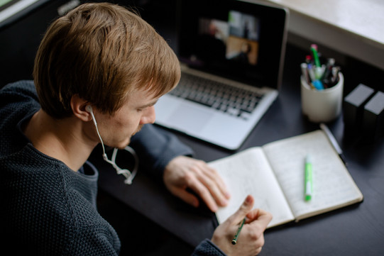 Lernen mit verschiedenen Medien Ein Student arbeitet mit Laptop und Notizbuch.